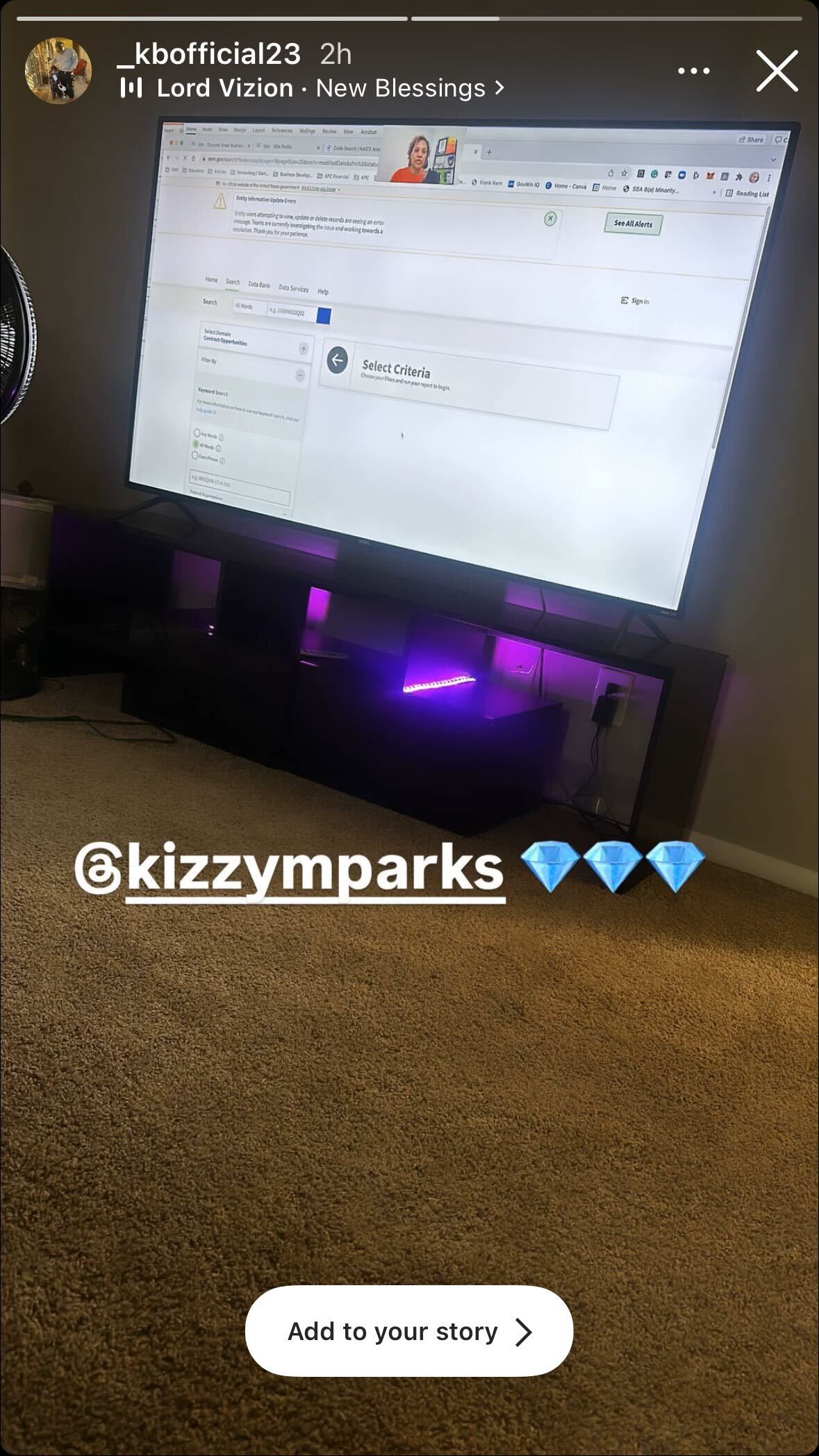 A TV screen displaying a webpage is mounted on a wall, with a low, dark TV stand beneath it. The text overlay reads "@kizzymparks" along with three diamond emojis.